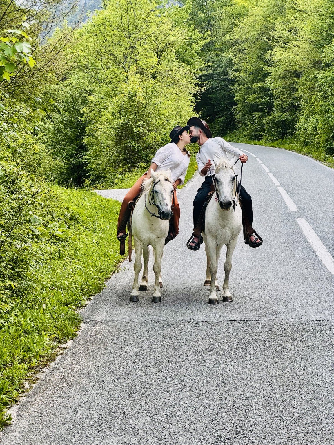 Rider leading two horses along a green road