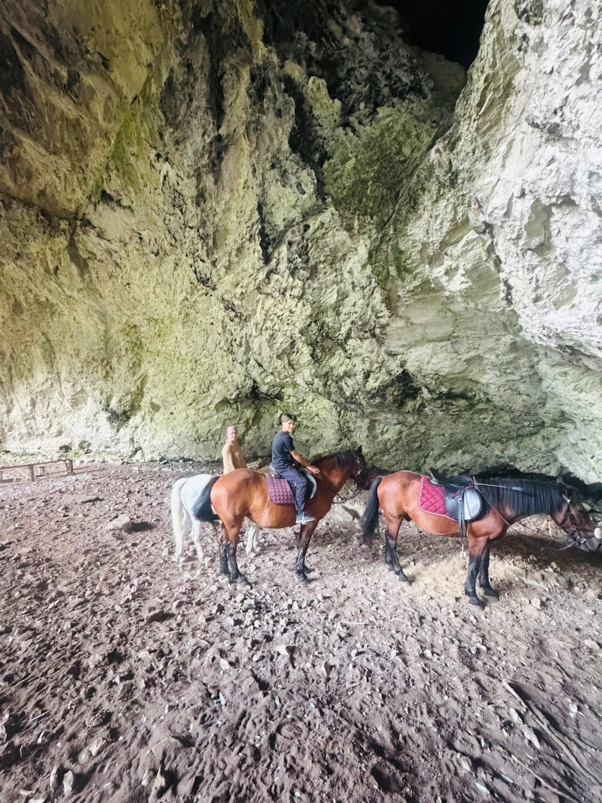 Horse riders beneath a rocky overhang